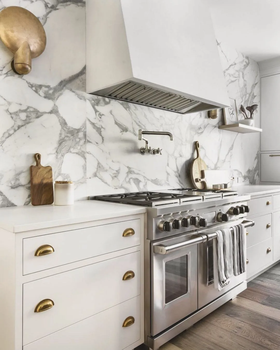 Marble slab backsplash behind a range with white cabinets